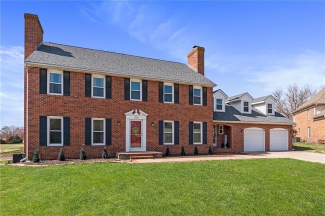 Colonial-style house with driveway, brick siding, a chimney, and a front lawn | Image 63