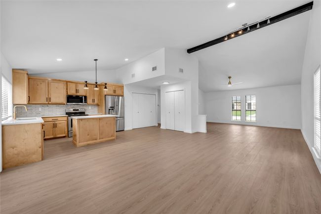 Kitchen featuring vaulted ceiling, appliances with stainless steel finishes, open floor plan, light countertops, and light brown cabinetry | Image 12