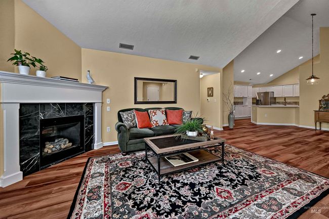 Living area featuring wood finished floors, lofted ceiling, recessed lighting, and a high end fireplace | Image 4