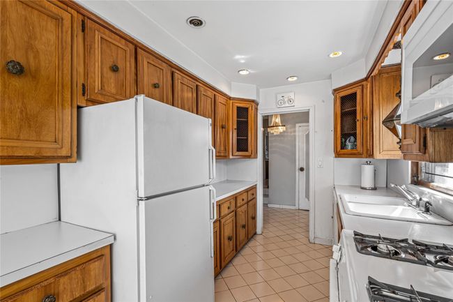 Kitchen with a sink, brown cabinets, and white appliances | Image 6