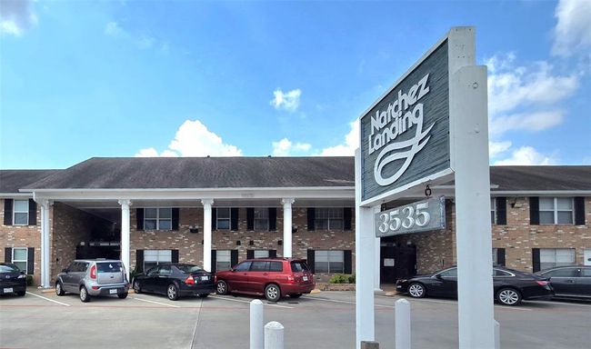 This photo shows a two-story brick building with white columns and a sign reading "Natchez Landing" at 3535. The building has a classic look, with parking spaces in front. Ideal for potential home buyers seeking a traditional style with convenient parking. | Image 27