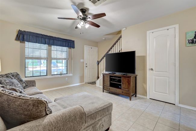Living room with light tile patterned floors, a ceiling fan, baseboards, and stairs | Image 11