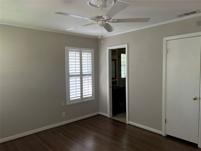 Unfurnished bedroom with ornamental molding, dark wood-type flooring, connected bathroom, and ceiling fan | Image 18