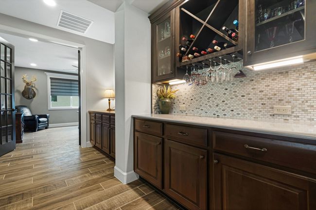 Indoor dry bar with tasteful backsplash, wood finish floors, baseboards, and recessed lighting | Image 11