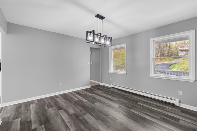 Unfurnished dining area with dark wood-style flooring, a notable chandelier, baseboard heating, and baseboards | Image 12