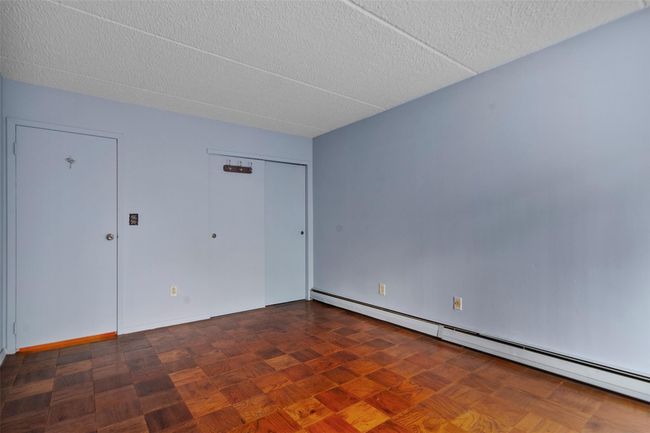 Unfurnished bedroom with a baseboard heating unit, a textured ceiling, and a closet | Image 19