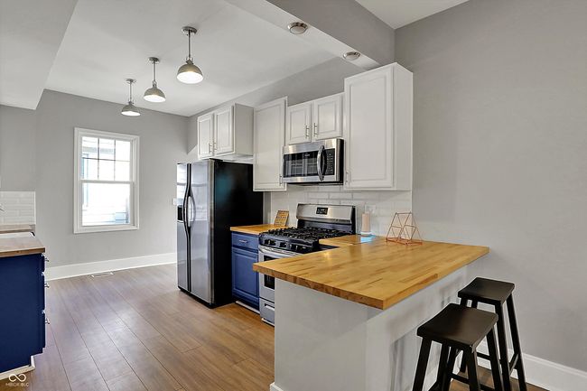 kitchen featuring butcher block counters, blue cabinets, tasteful backsplash, and stainless steel appliances | Image 14