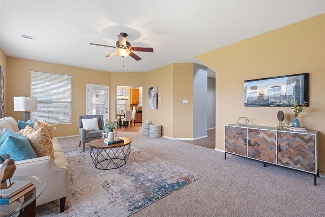 Carpeted living area featuring a ceiling fan and baseboards | Image 11
