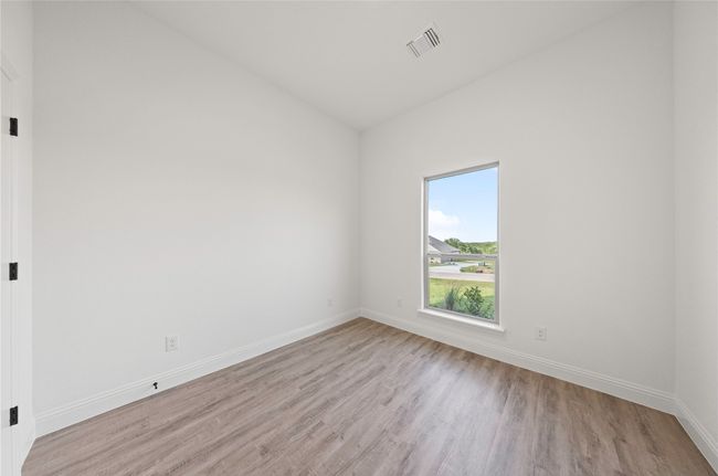 Unfurnished room featuring light wood finished floors, baseboards, and lofted ceiling | Image 7