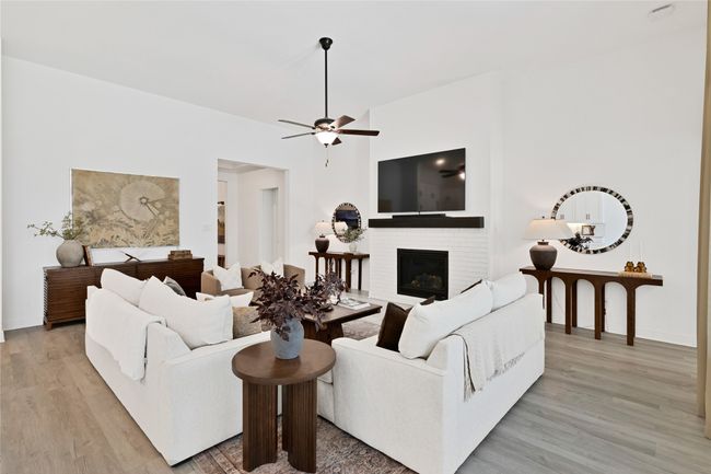 Living area with light wood finished floors, a fireplace, ceiling fan, and baseboards | Image 12