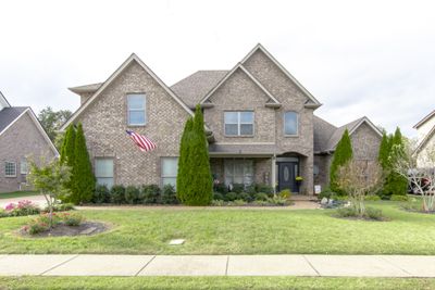 Welcome to this stunning front yard with a great covered porch. The yard is well maintained with beautiful seasonal flowers and mature trees for color to this lovely brick home. | Image 3