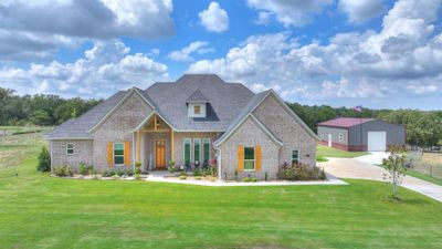 View of front of house featuring an outdoor structure, a garage, a front lawn, and covered porch | Image 2