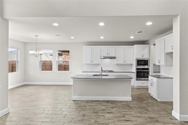 Kitchen featuring stainless steel appliances, baseboards, under cabinet range hood, a chandelier, and recessed lighting | Image 11