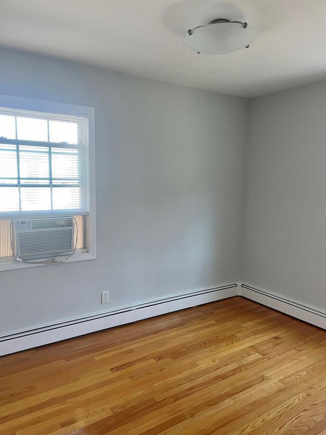 Unfurnished room featuring light wood-style flooring, cooling unit, and a baseboard heating unit | Image 22