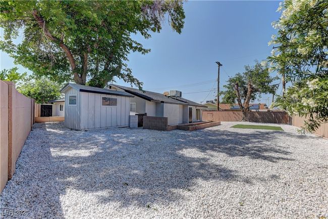 Back of house with board and batten siding, a fenced backyard, and an outdoor structure | Image 34