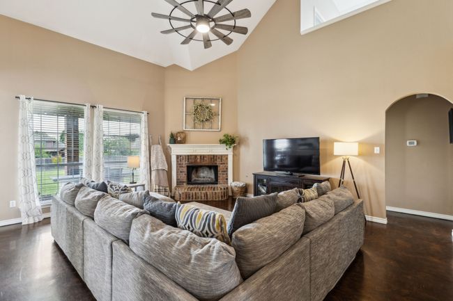 Living room with ceiling fan, arched walkways, a brick fireplace, and high vaulted ceiling | Image 6