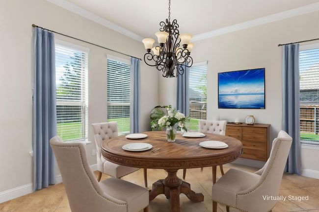 Dining room with a chandelier, ornamental molding, baseboards, healthy amount of natural light, and light tile patterned floors | Image 6