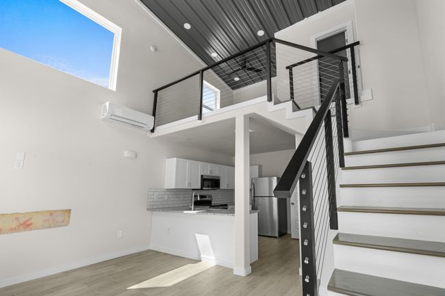 Stairway featuring an AC wall unit, a towering ceiling, and wood finished floors | Image 12