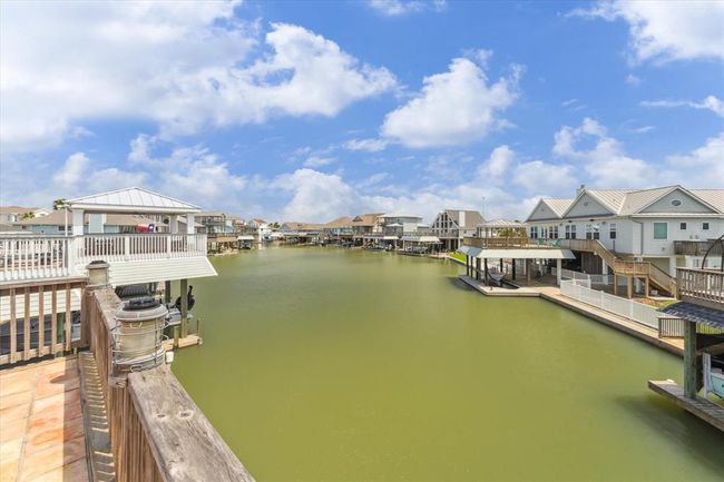 Waterfront view of canal-side homes with private docks and decks, offering a serene, picturesque setting under a bright blue sky. Ideal for boating enthusiasts and those seeking a tranquil living environment. | Image 31
