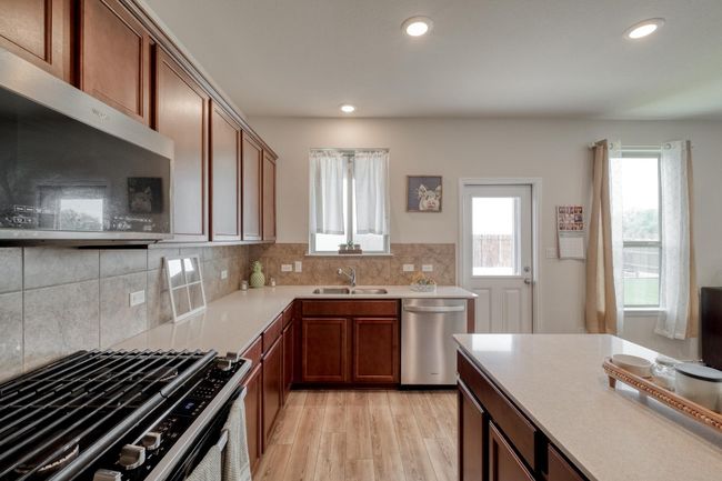 Kitchen with light countertops, a sink, backsplash, appliances with stainless steel finishes, and light wood-type flooring | Image 17