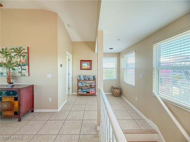 Corridor with lofted ceiling, light tile patterned floors, baseboards, and an upstairs landing | Image 22