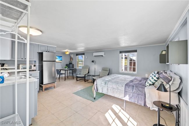 Bedroom with sink, light tile patterned floors, a wall mounted AC, crown molding, and stainless steel fridge | Image 23