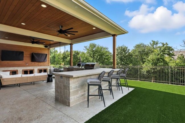 View of patio with exterior kitchen, an outdoor living space, and a ceiling fan | Image 33