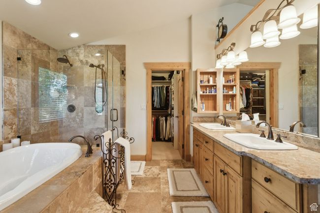Bathroom featuring a stall shower, a walk in closet, double vanity, a bath, and vaulted ceiling | Image 28