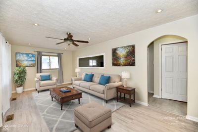 Virtually Staged Living Room with ceiling fan & arch to hallway. | Image 2