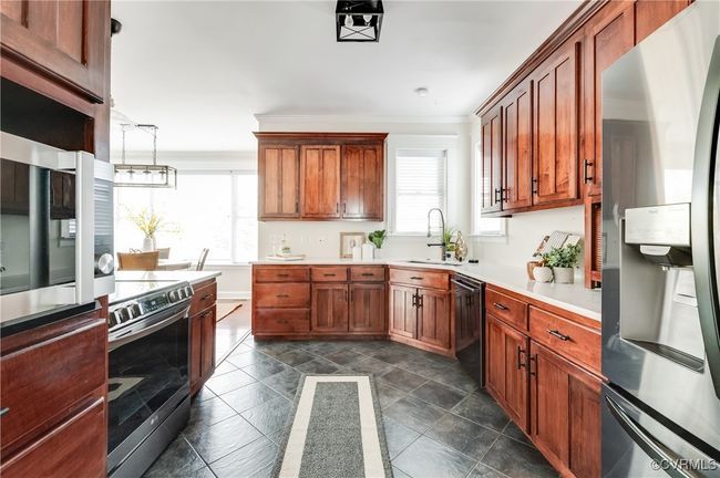Kitchen featuring crown molding, light countertops, a sink, appliances with stainless steel finishes, and brown cabinets | Image 12