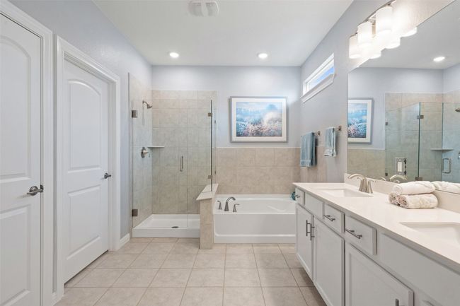 The ensuite bathroom with dual vanities, garden tub, walk-in frameless glass shower, and an expansive walk-in closet. | Image 22