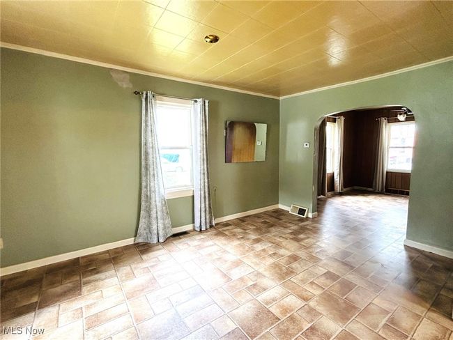 Spare room featuring arched walkways, ornamental molding, baseboards, and stone finish flooring | Image 7