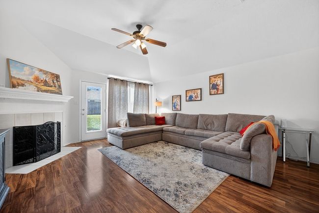 Living area featuring lofted ceiling, ceiling fan, wood finished floors, and a tiled fireplace | Image 17
