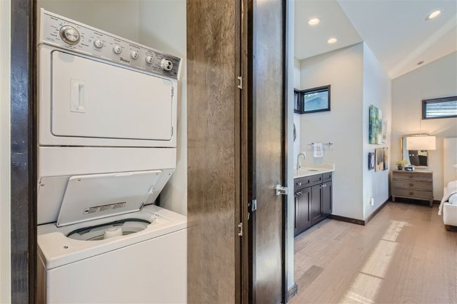 Clothes washing area featuring stacked washer / drying machine, recessed lighting, light wood-style floors, a sink, and laundry area | Image 9