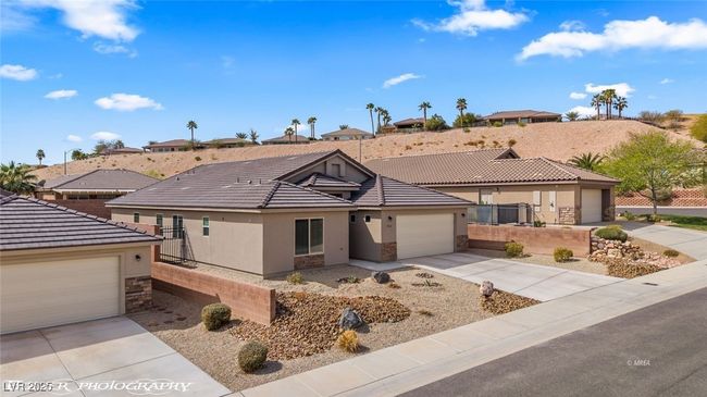 Ranch-style house with stone siding, stucco siding, a tiled roof, and concrete driveway | Image 62