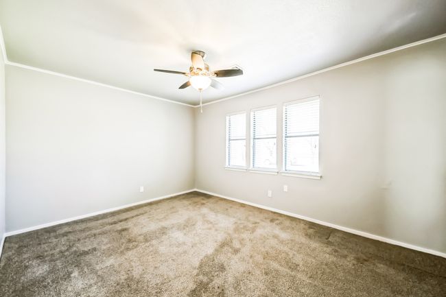 Carpeted spare room with a ceiling fan, baseboards, and ornamental molding | Image 14