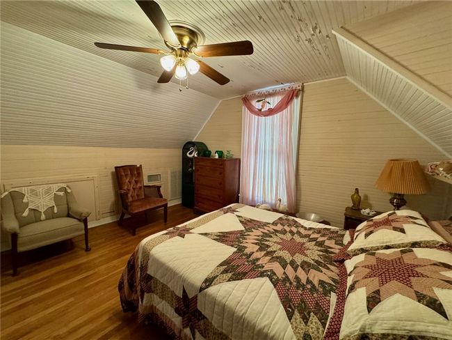 Bedroom with lofted ceiling, wood finished floors, wood ceiling, wooden walls, and a ceiling fan | Image 31