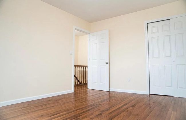 Unfurnished bedroom with wood finished floors, a closet, and baseboards | Image 14