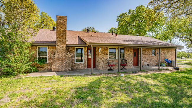 View of front of home featuring a patio, a chimney, a shingled roof, and a front lawn | Image 35