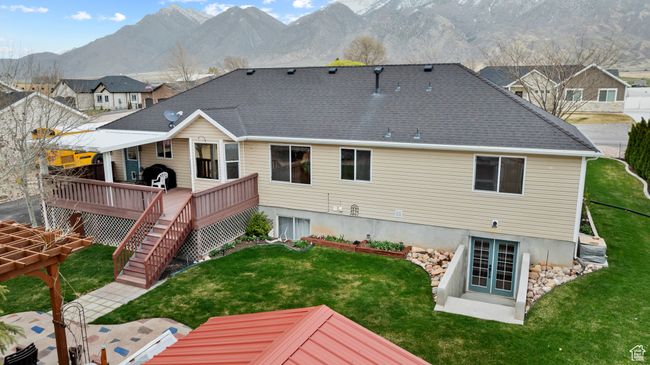 Rear view of house featuring a deck with mountain view, stairs, a shingled roof, french doors, and a yard | Image 36