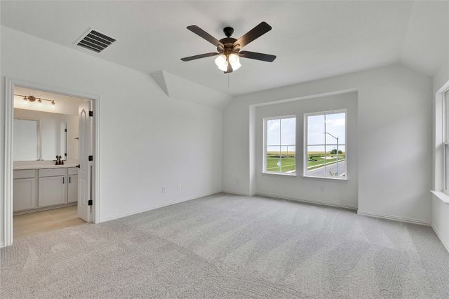 Unfurnished bedroom featuring lofted ceiling, light colored carpet, ensuite bathroom, and a ceiling fan | Image 5