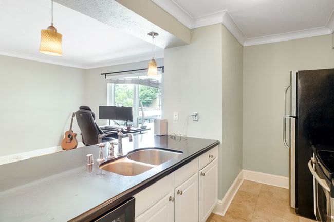 Kitchen with stainless steel appliances, crown molding, white cabinetry, a sink, and hanging light fixtures | Image 7