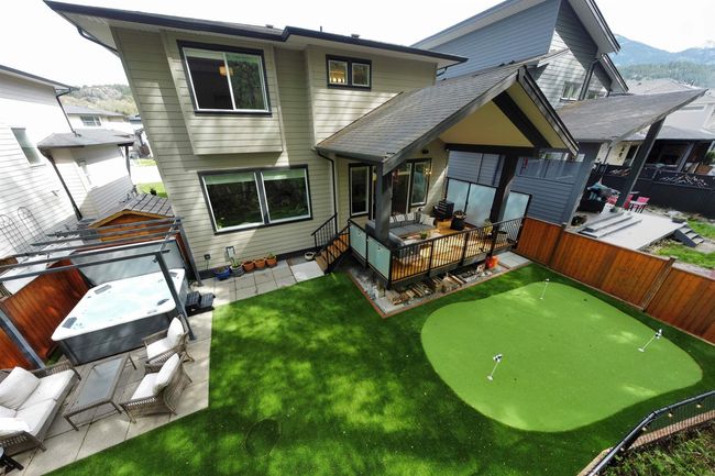 Rear view of property featuring a fenced backyard, a deck with mountain view, a hot tub, an outdoor hangout area, and a patio area | Image 32