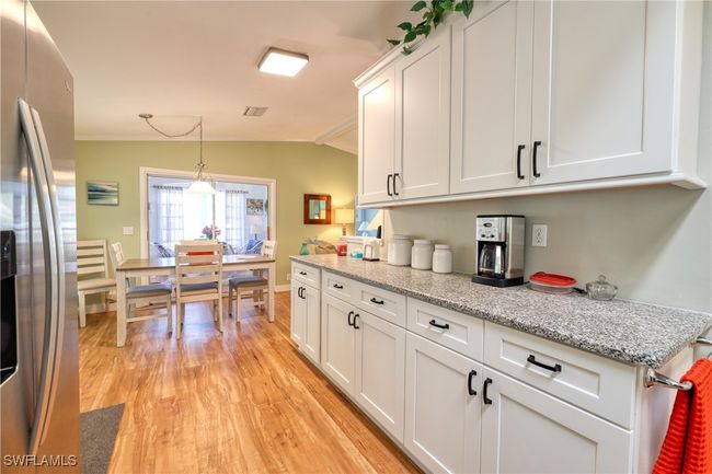 Kitchen with stainless steel fridge, light wood-type flooring, vaulted ceiling, pendant lighting, and white cabinets | Image 4