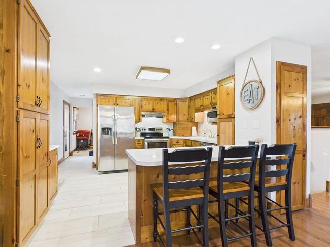 Kitchen featuring a breakfast bar, light countertops, under cabinet range hood, stainless steel appliances, and a sink | Image 35