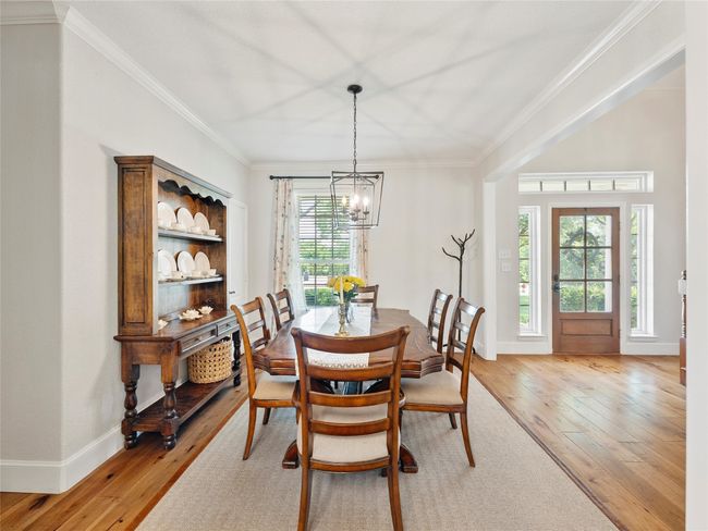 Dining space with ornamental molding, light wood-style flooring, and a chandelier | Image 10
