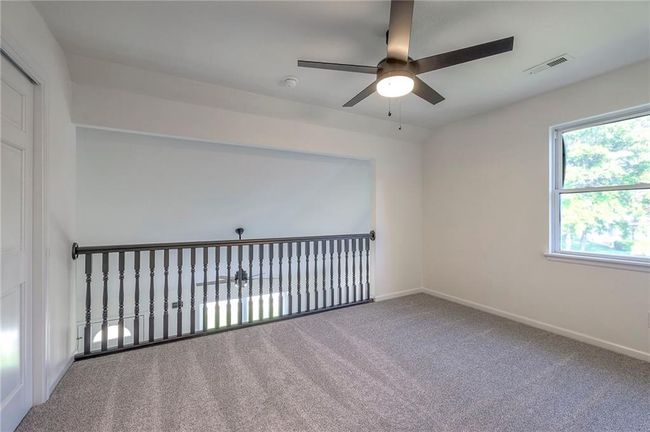 Carpeted empty room featuring a ceiling fan and a smoke detector | Image 17