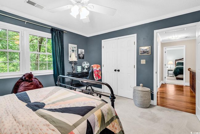 Bedroom with attic access, crown molding, a closet, carpet flooring, and a ceiling fan | Image 23