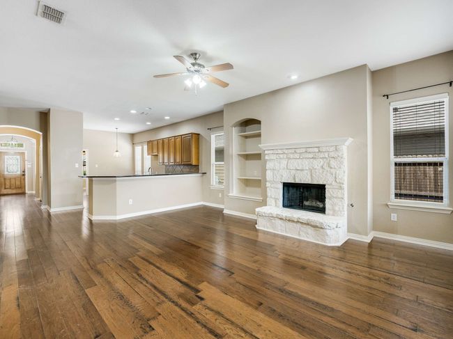 Unfurnished living room with ceiling fan, dark wood-style flooring, a fireplace, plenty of natural light, and recessed lighting | Image 9