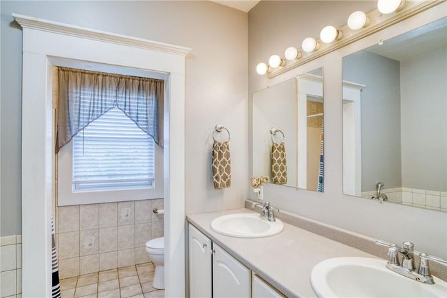 Bathroom featuring toilet, tile patterned flooring, tile walls, and double vanity | Image 13